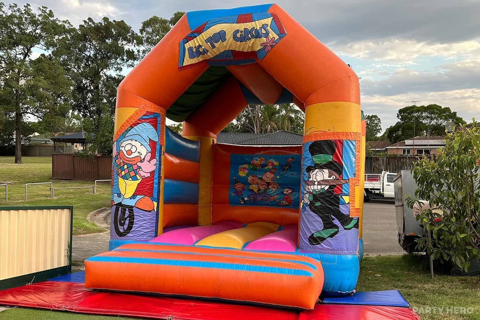 Big Top Circus jumping castle with an orange roof set up in a park
