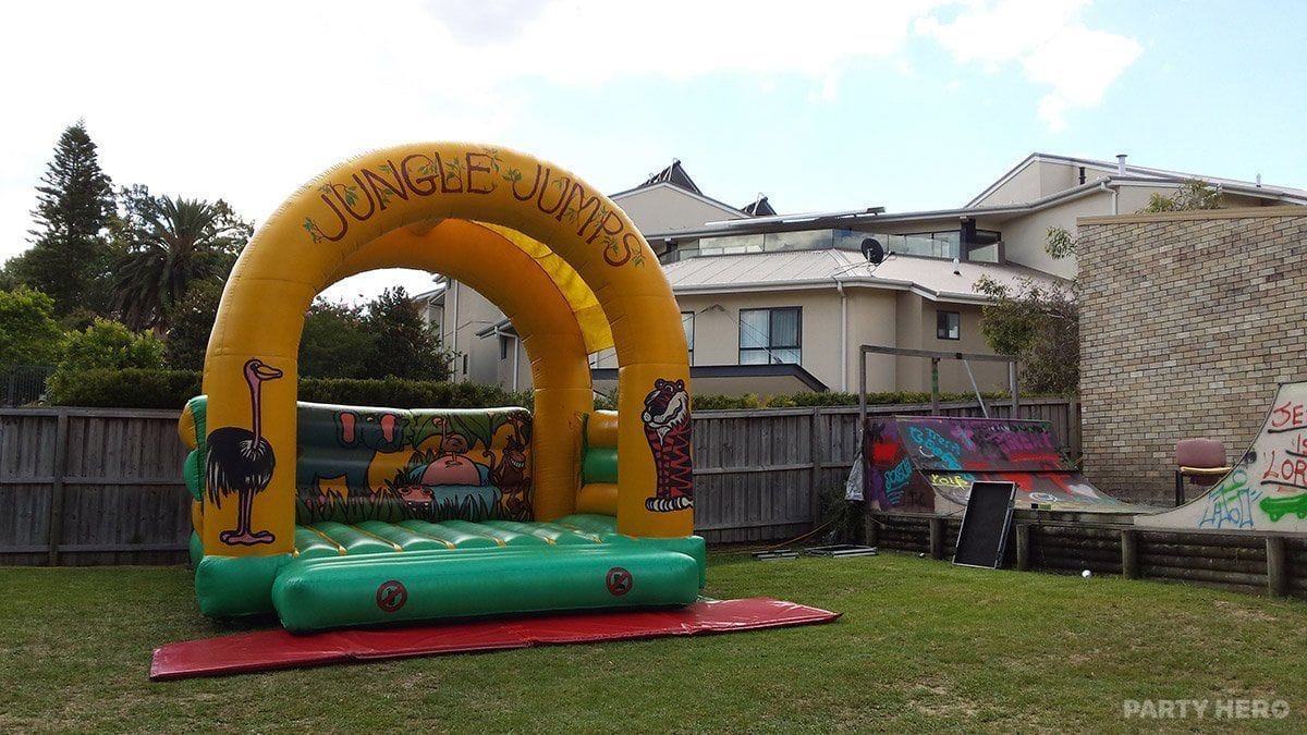 Jungle Jumps castle set up on a lawn beside a building