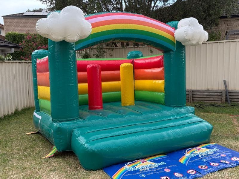 Open-front rainbow toddler castle with cloud tops and character poles, set up in a Sydney backyard