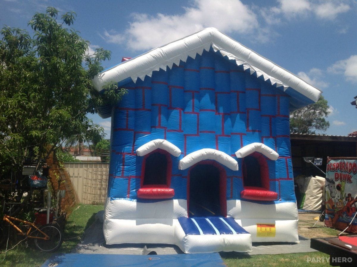 Blue snow-house jumping castle with white rooftop set up in a backyard