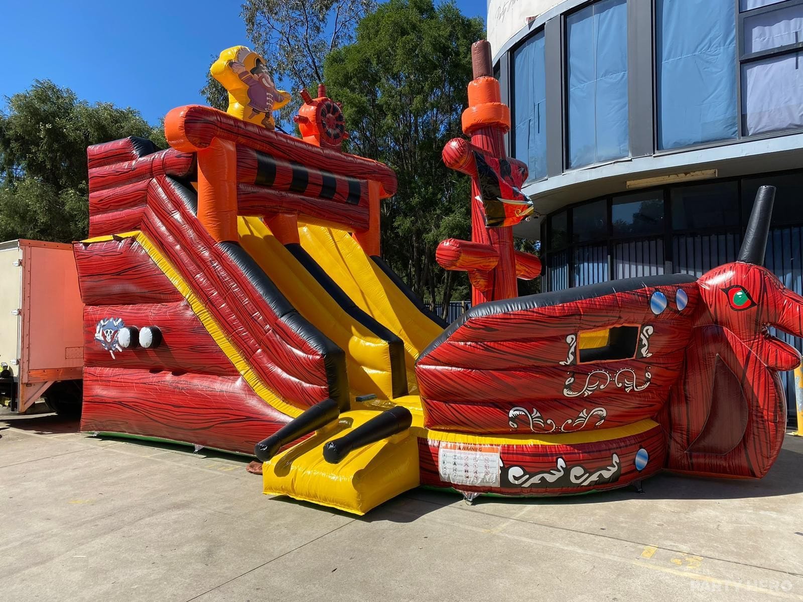Red pirate ship castle with a slide, inflated on a Sydney street before a party