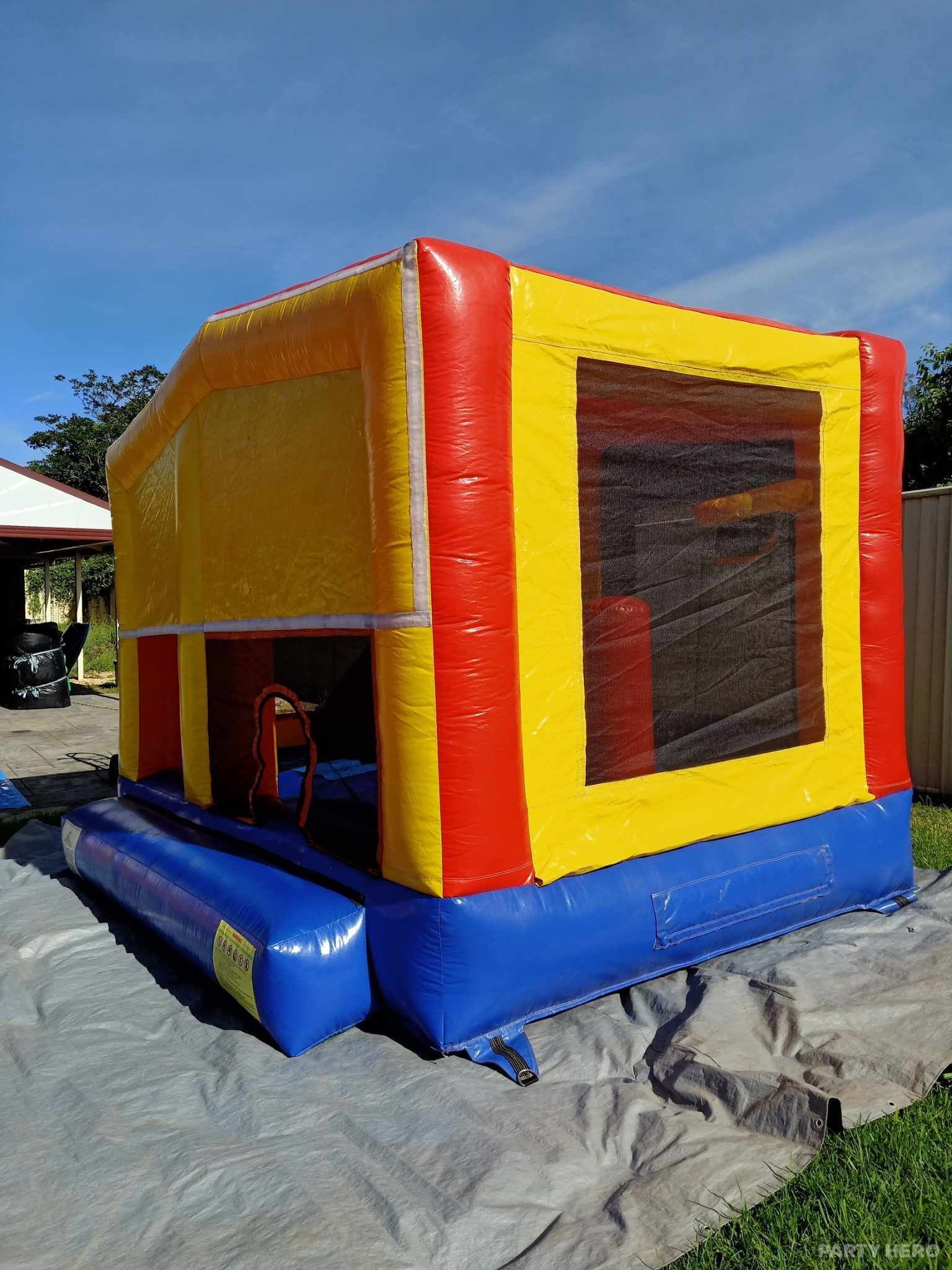 Red and yellow plain jumping castle with netted windows in a south-west Sydney backyard