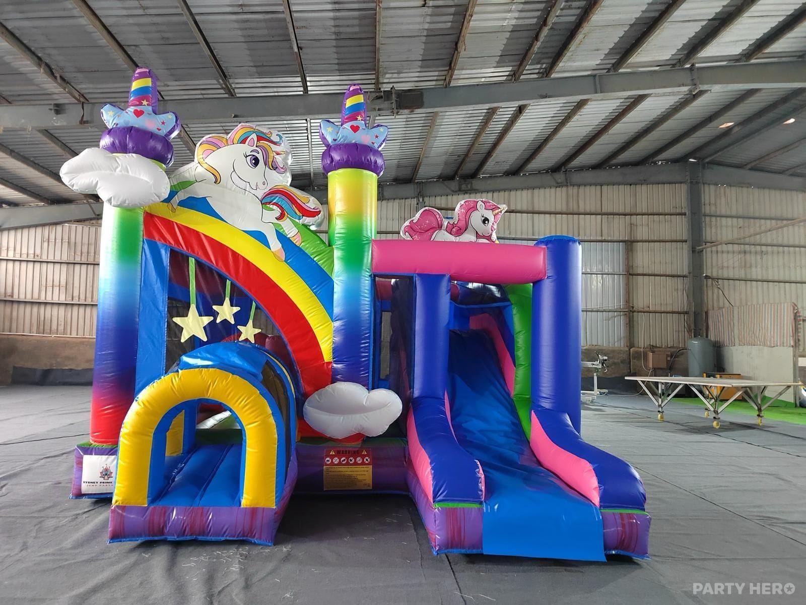 Rainbow unicorn combo castle with twin slides and cloud decorations