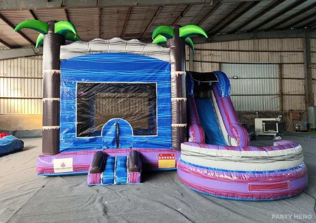 Tropical combo castle with palm trees and a pink slide