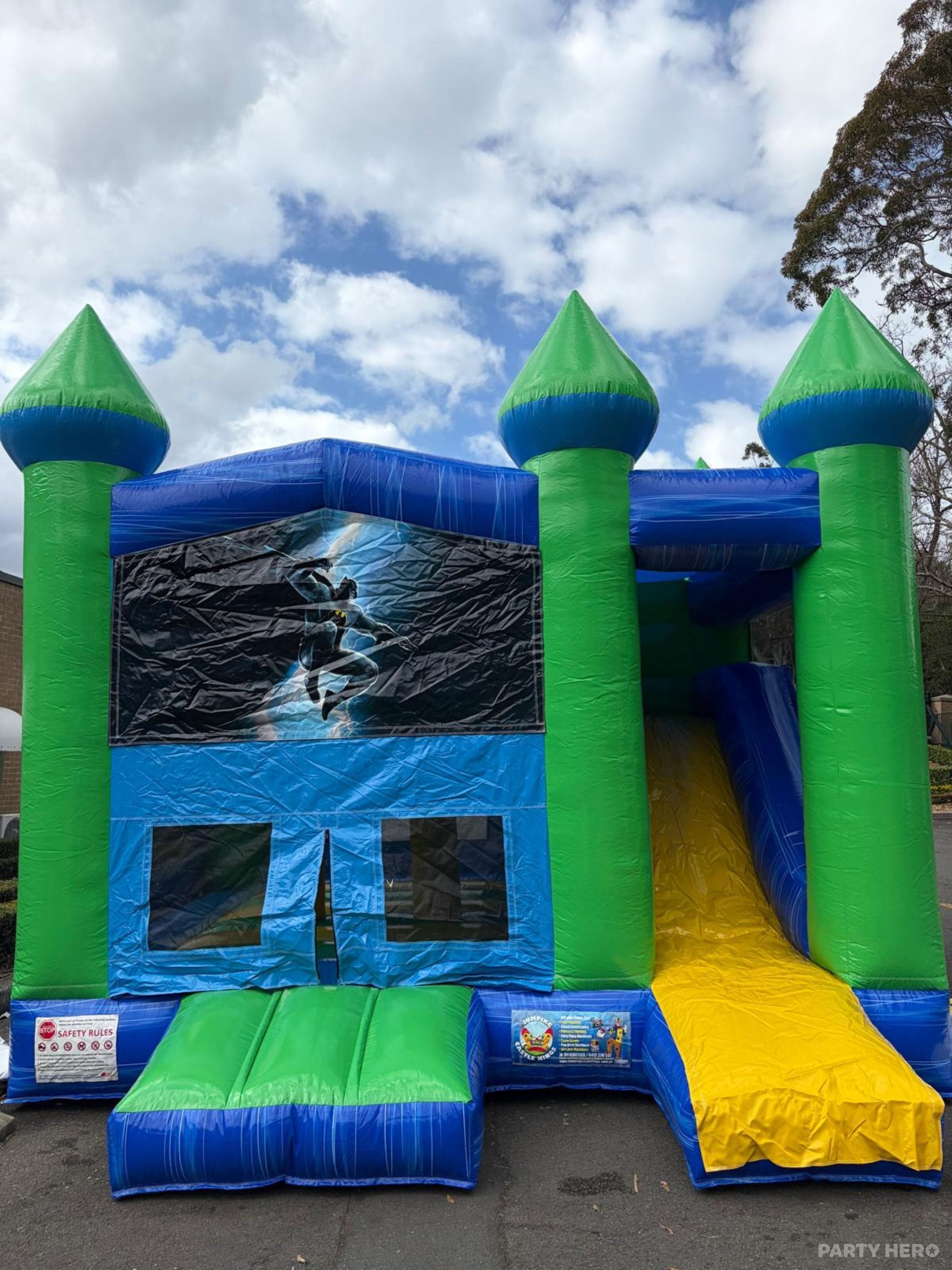 Blue and green combo castle with a yellow slide under a cloudy sky