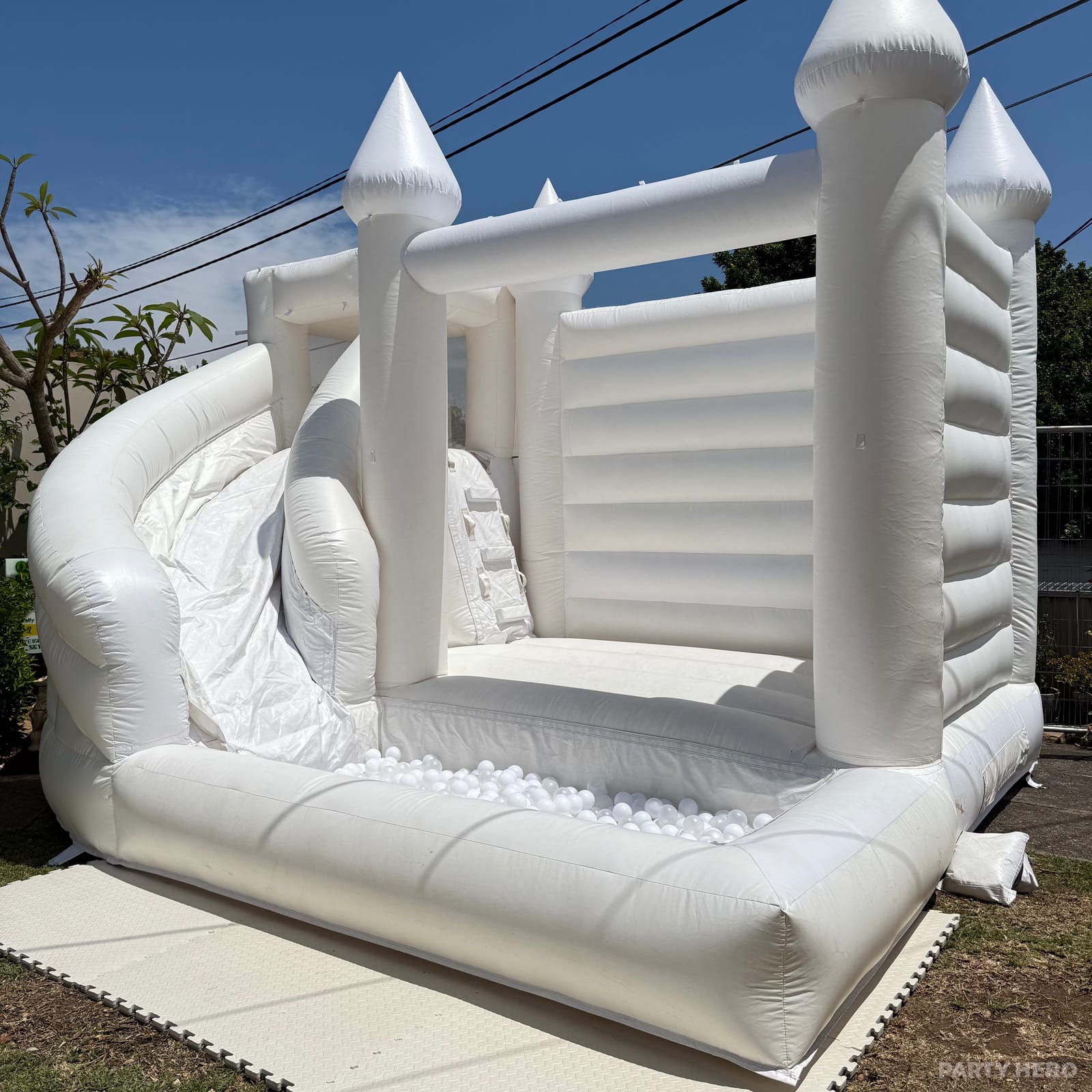 White turreted bounce house with a slide set up outdoors
