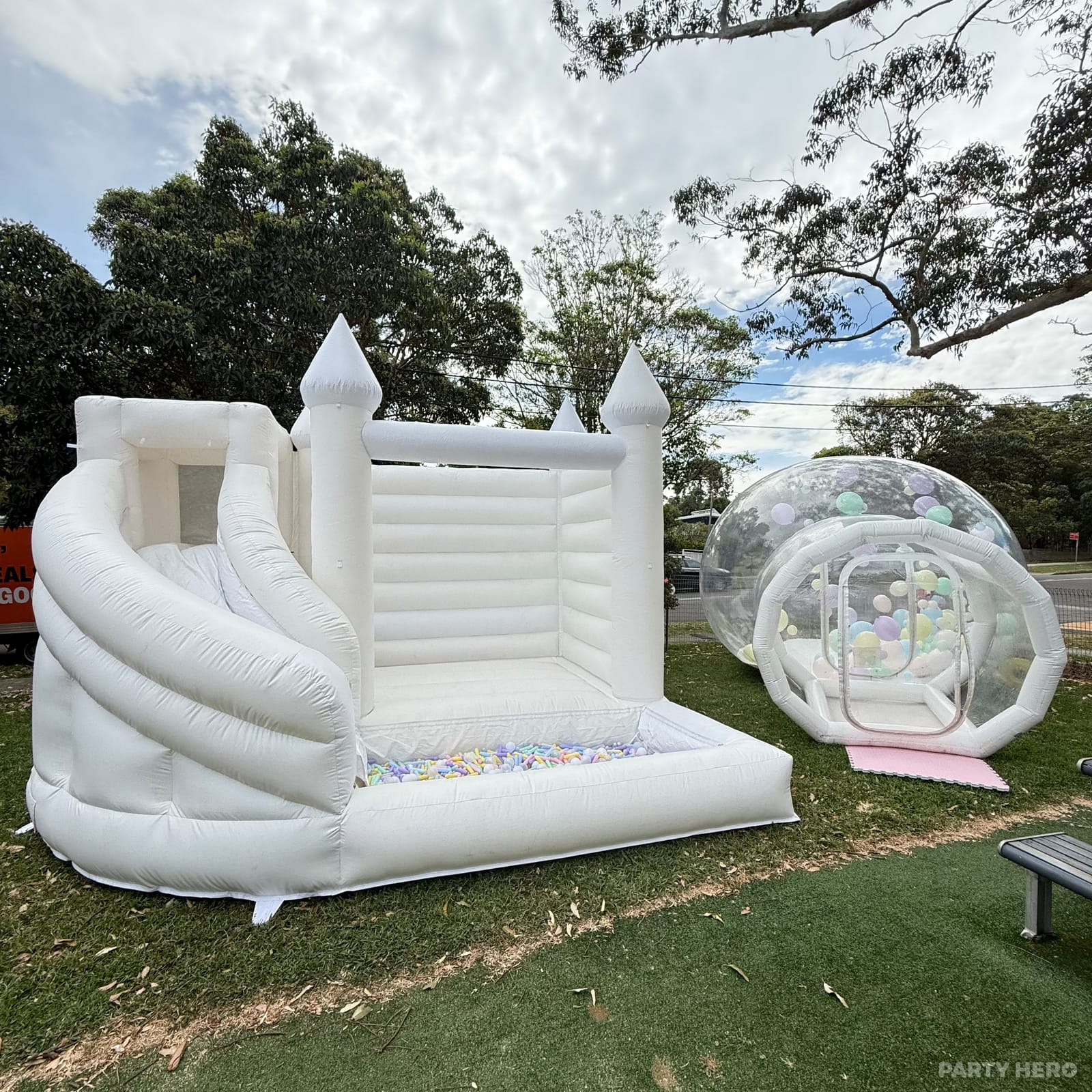 White castle bounce house with a slide beside a clear bubble dome in a garden