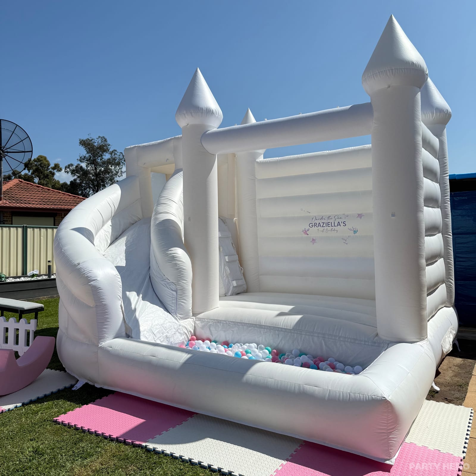 White castle bounce house with a curved slide and ball pit