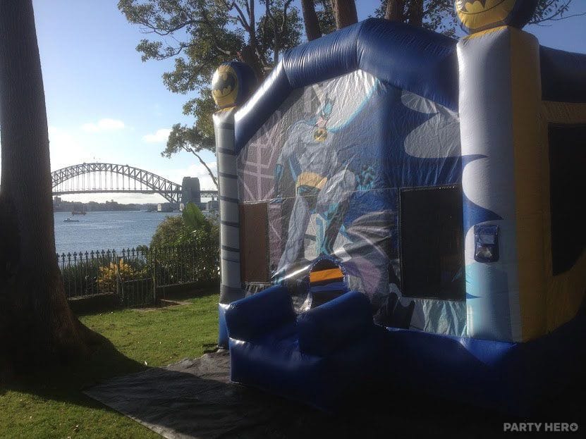 Batman jumping castle set up on a harbourside lawn with the Sydney Harbour Bridge behind